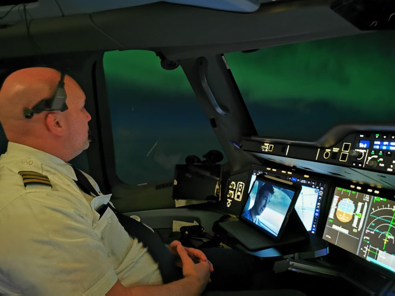 Pilot seated on the flight deck with a tablet in front of the night view